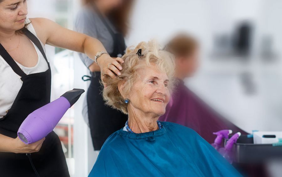 Frisörin föhnt Bewohnerin die Haare